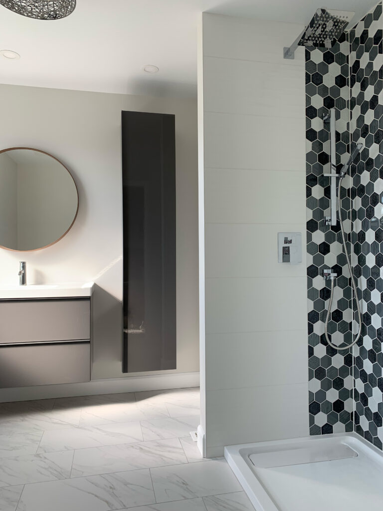 Bathroom with round mirror and patterned shower tile